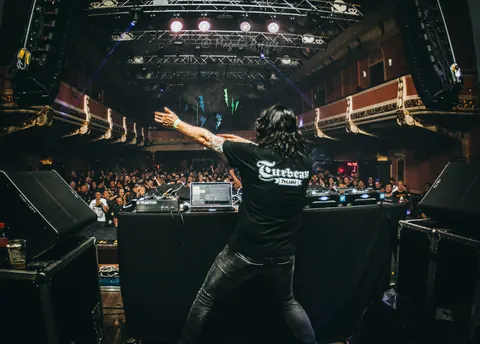 DJ Turbeau with his arms spread towards a packed hall at Vooruit, Gent (April 2019)