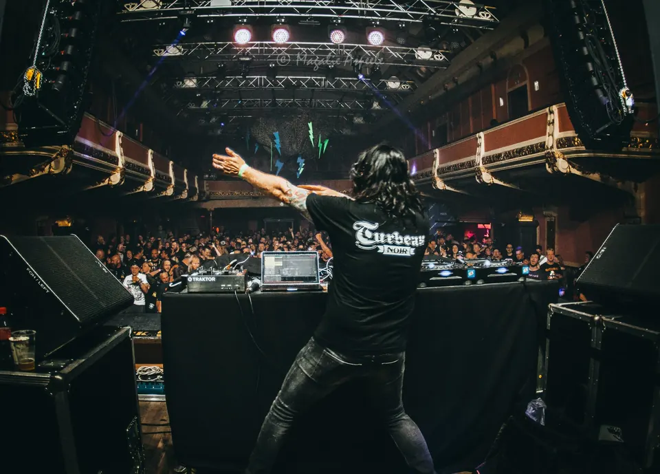 DJ Turbeau with his arms spread towards a packed hall at Vooruit, Gent (April 2019)